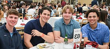 Four students pose at the dinner table for a photo.